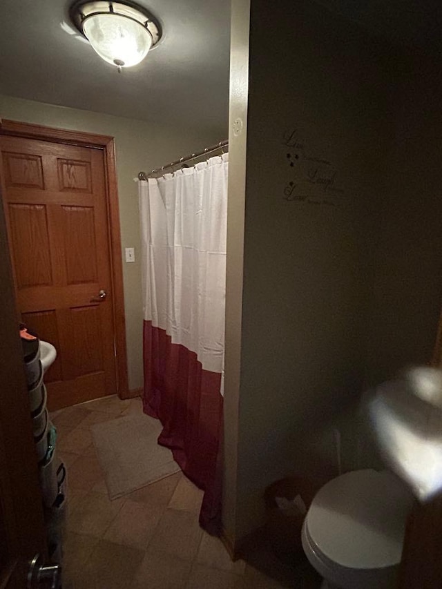 bathroom featuring toilet, tile patterned floors, and curtained shower