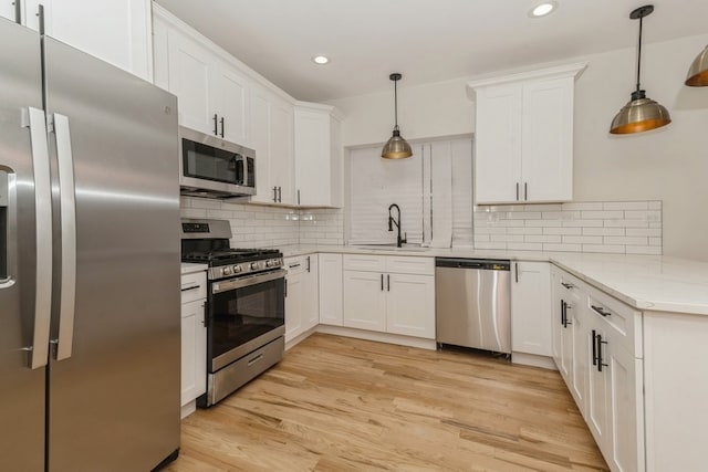 kitchen with white cabinets, decorative light fixtures, light hardwood / wood-style floors, and stainless steel appliances