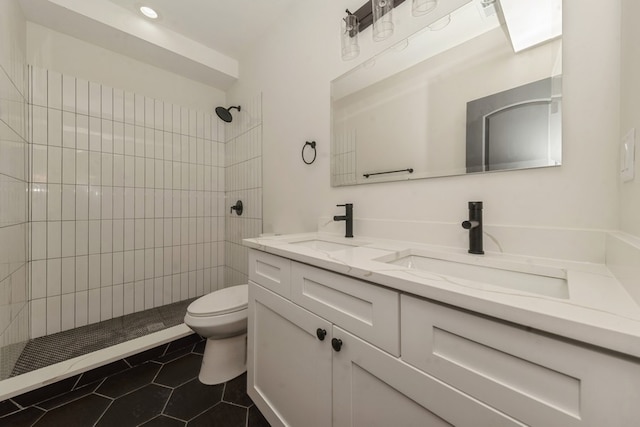 bathroom featuring tile patterned flooring, vanity, toilet, and tiled shower