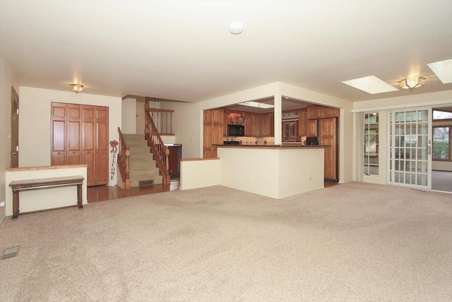 unfurnished living room with carpet flooring and a skylight