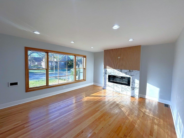 unfurnished living room with light wood-style flooring, recessed lighting, a fireplace, visible vents, and baseboards