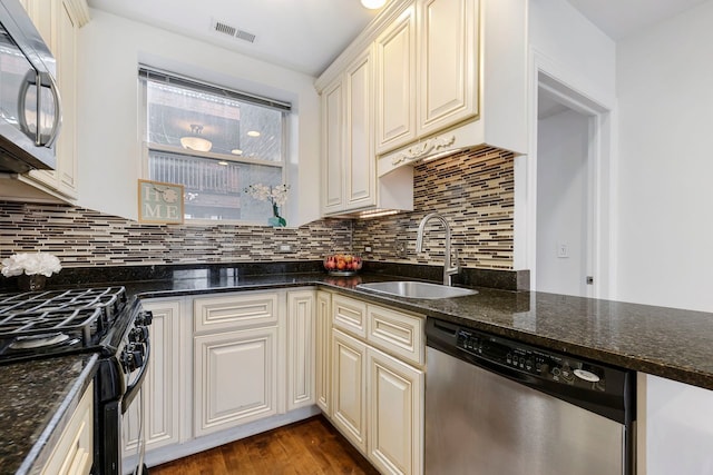 kitchen featuring dark stone counters, sink, dark wood-type flooring, and appliances with stainless steel finishes