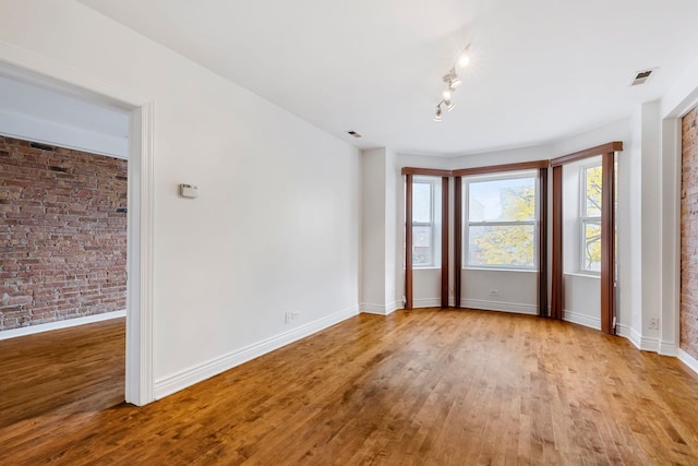 spare room featuring light hardwood / wood-style flooring and brick wall