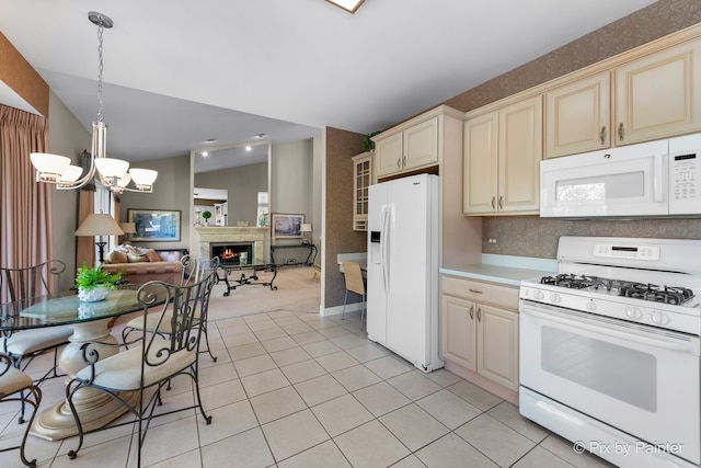 kitchen featuring light tile patterned flooring, lofted ceiling, hanging light fixtures, white appliances, and cream cabinetry