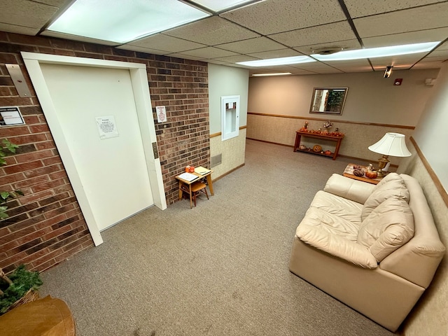 carpeted living room featuring a paneled ceiling, electric panel, and brick wall