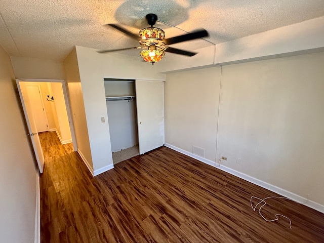 unfurnished bedroom featuring a textured ceiling, ceiling fan, a closet, and dark hardwood / wood-style floors