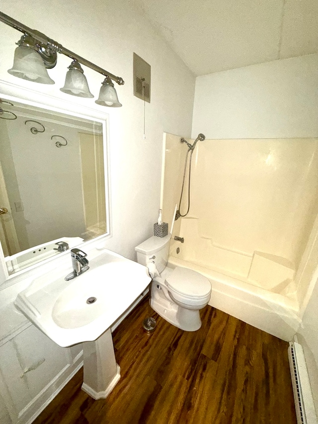 full bathroom featuring sink, baseboard heating, hardwood / wood-style floors, toilet, and bathtub / shower combination