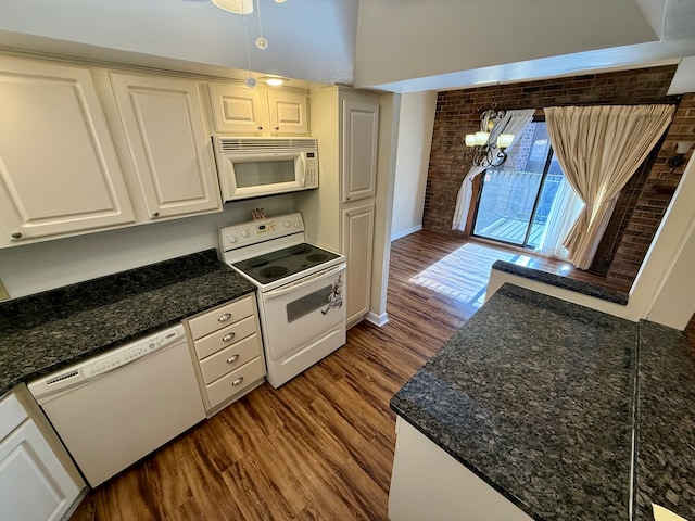 kitchen with white appliances, dark wood-type flooring, a notable chandelier, white cabinetry, and brick wall