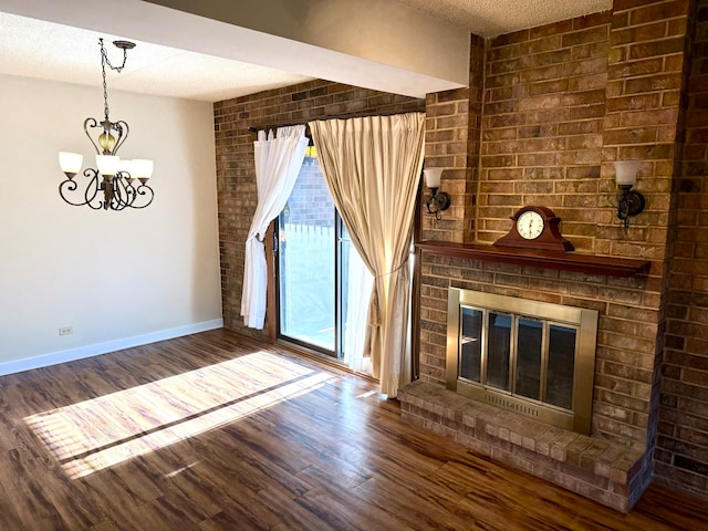 unfurnished living room featuring a chandelier, a fireplace, wood-type flooring, and a textured ceiling