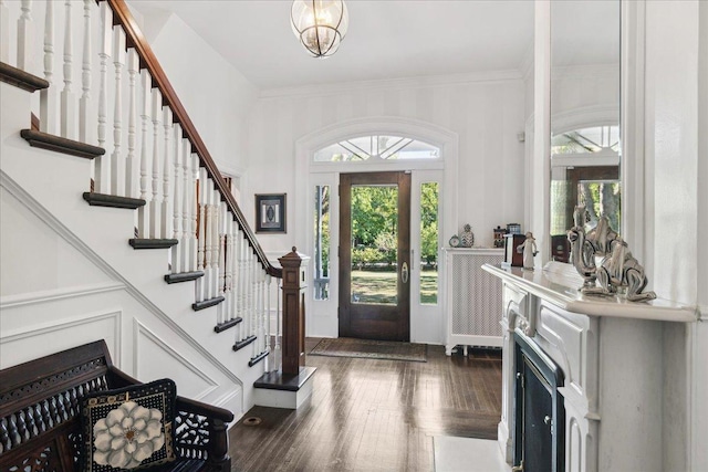 entryway with dark hardwood / wood-style flooring, an inviting chandelier, and crown molding