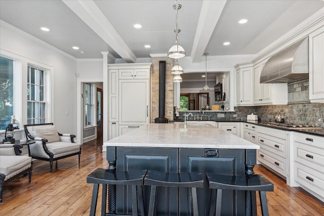 kitchen featuring custom exhaust hood, light hardwood / wood-style floors, a breakfast bar area, and hanging light fixtures