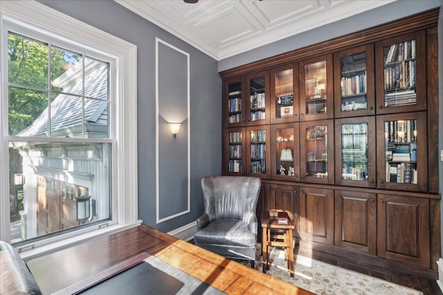 living area with wood-type flooring and ornamental molding