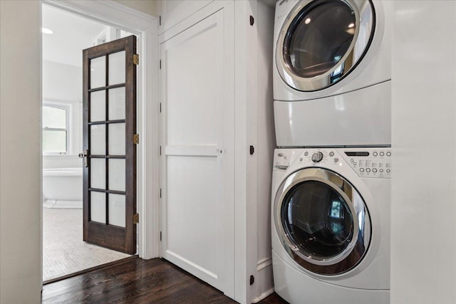 clothes washing area featuring french doors, dark hardwood / wood-style floors, and stacked washer and clothes dryer