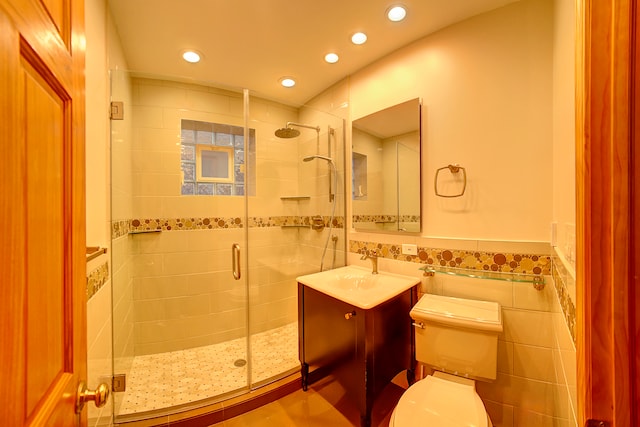 bathroom with vanity, a shower with door, toilet, and tile walls