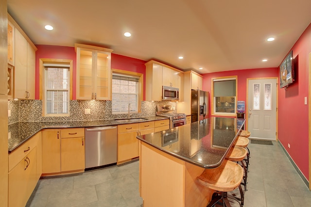 kitchen with light brown cabinets, a center island, stainless steel appliances, and sink