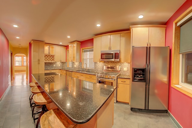 kitchen featuring a kitchen bar, stainless steel appliances, plenty of natural light, and sink