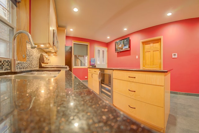 kitchen with sink, light brown cabinets, beverage cooler, decorative backsplash, and range