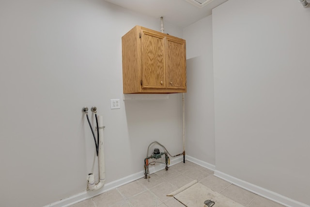 clothes washing area with washer hookup, light tile patterned flooring, and cabinets