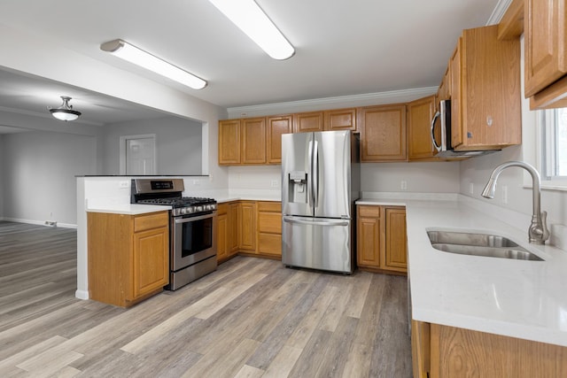 kitchen with kitchen peninsula, appliances with stainless steel finishes, ornamental molding, sink, and light hardwood / wood-style floors