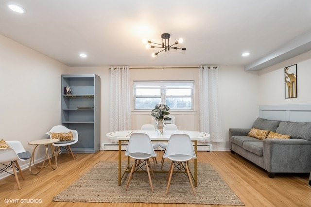 dining room with light wood-type flooring, baseboard heating, and a chandelier