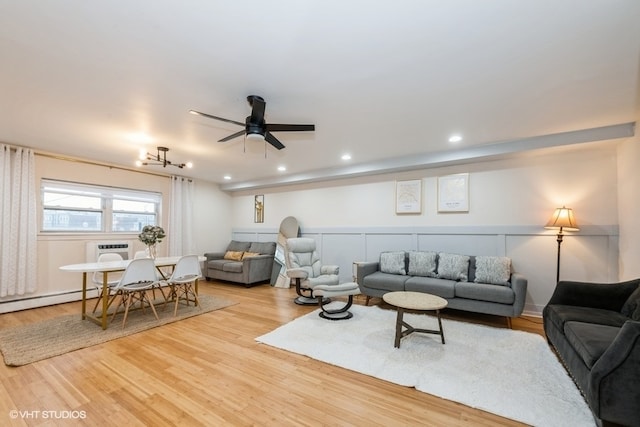 living room featuring ceiling fan, a baseboard radiator, a wall unit AC, and light hardwood / wood-style flooring