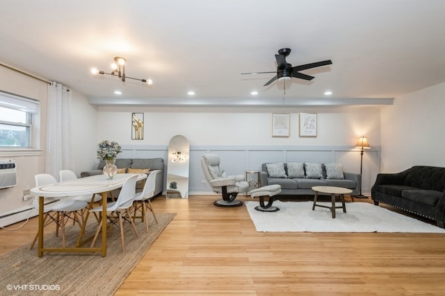 living room featuring ceiling fan with notable chandelier and light hardwood / wood-style flooring