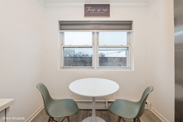 dining room featuring hardwood / wood-style floors, a wealth of natural light, and a baseboard heating unit