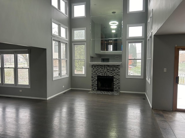 18502 River Rd, Hazel Crest, IL 60429 - unfurnished living room with a towering ceiling, baseboards, a fireplace with flush hearth, and dark wood-style flooring