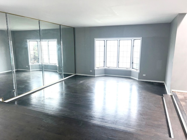 empty room with dark hardwood / wood-style floors and a healthy amount of sunlight