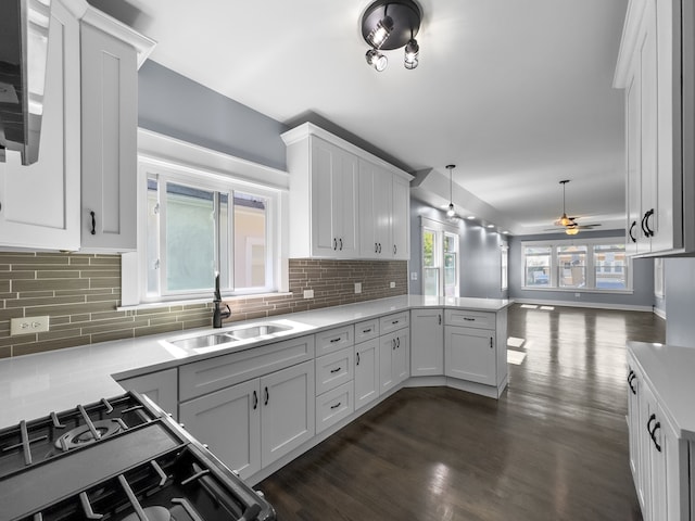 kitchen with backsplash, sink, ceiling fan, gas stove, and white cabinetry