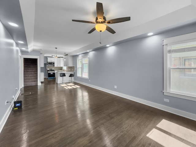 unfurnished living room with ceiling fan and dark hardwood / wood-style flooring