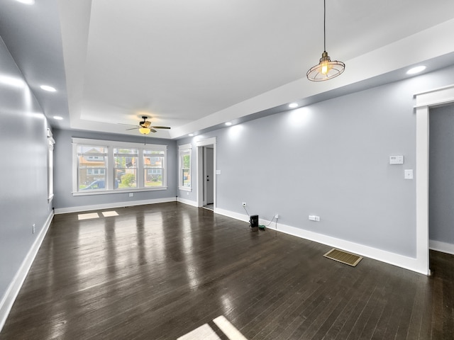 unfurnished living room with dark hardwood / wood-style flooring, a raised ceiling, and ceiling fan