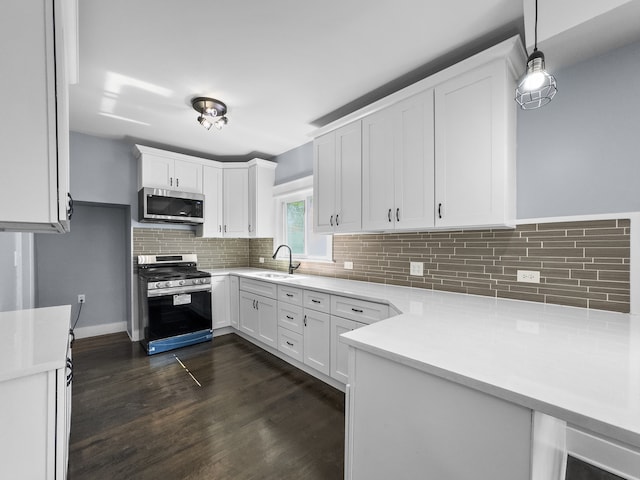 kitchen featuring gas range, white cabinetry, hanging light fixtures, and sink