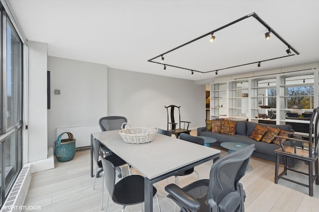 dining space with track lighting and light wood-type flooring