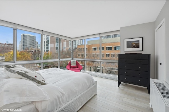 bedroom with radiator, a wall of windows, and light wood-type flooring