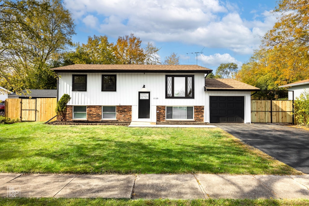 bi-level home with a garage, a front lawn, and a storage shed