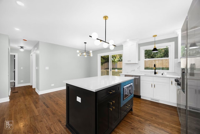 kitchen featuring sink, hanging light fixtures, a kitchen island, dark hardwood / wood-style floors, and white cabinets