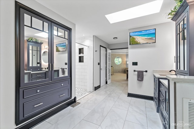 bathroom with a tile shower, a skylight, and vanity