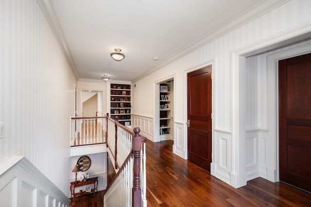 hallway with dark hardwood / wood-style floors, built in features, and crown molding