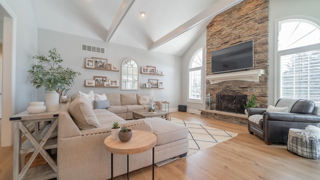 living room with beamed ceiling, high vaulted ceiling, a fireplace, and light hardwood / wood-style floors