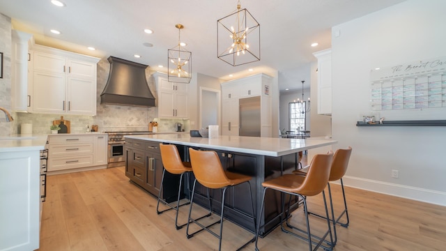 kitchen with white cabinetry, sink, premium appliances, custom exhaust hood, and hanging light fixtures