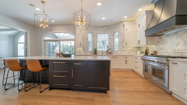 kitchen with hanging light fixtures, double oven range, a kitchen island, custom range hood, and white cabinets