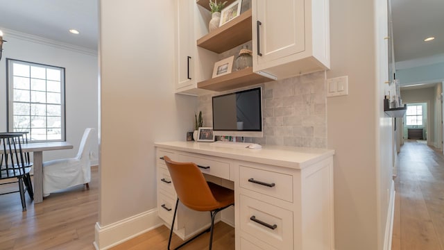 office featuring crown molding, built in desk, and light wood-type flooring