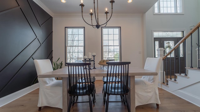 dining space with crown molding, a notable chandelier, and light hardwood / wood-style flooring