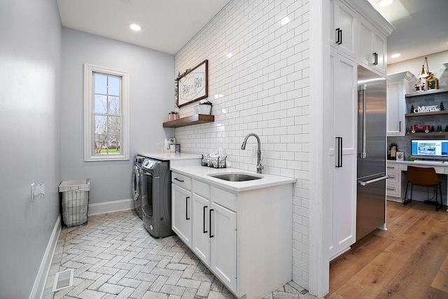 laundry area with cabinets, sink, washing machine and clothes dryer, and light hardwood / wood-style floors