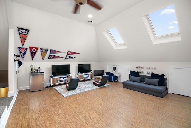 living room featuring hardwood / wood-style flooring, ceiling fan, and lofted ceiling with skylight