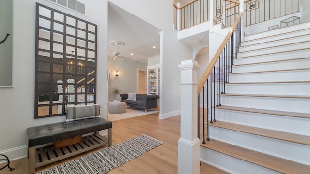 entryway featuring hardwood / wood-style flooring, a towering ceiling, and ceiling fan