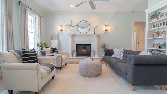 living room with built in shelves, ceiling fan, ornamental molding, and light hardwood / wood-style floors