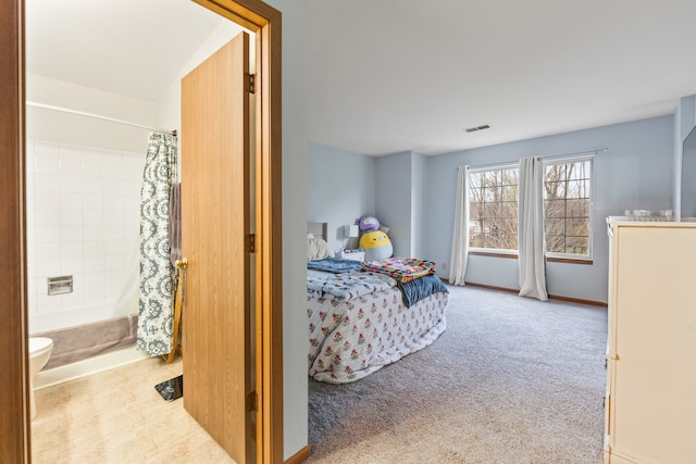 bedroom with light colored carpet and connected bathroom