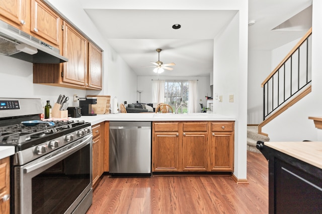 kitchen featuring kitchen peninsula, stainless steel appliances, ceiling fan, sink, and hardwood / wood-style floors